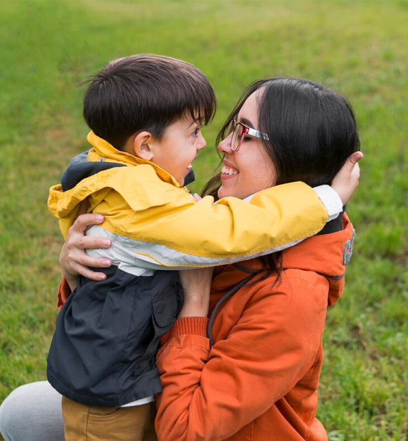 A young boy and his mother hugging.